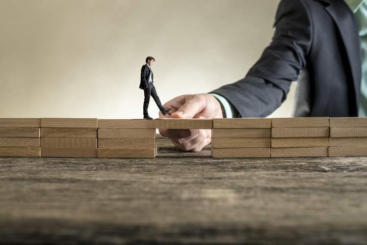 Stock photo man solving problems by building bridge with wooden block to span a gap for little businessman 674604469
